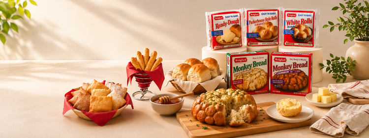 Table setting with Monkey Bread packages, bread, and condiments on a light background