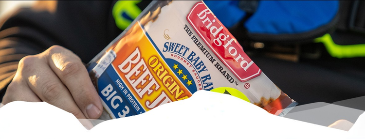 Hand holding a package of Sweet Baby Ray's Beef Jerky with blurred background