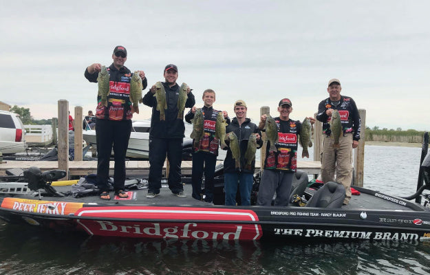 Bridgford fishing team holding caught fish while standing on a boat